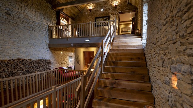 A wooden staircase with stone walls, a balcony, and a rustic interior. - Au Domaine de la Pommeraye & Spa (La Pommeraye)