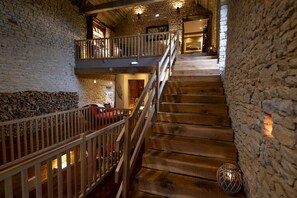 A wooden staircase with stone walls, a balcony, and a rustic interior. - Au Domaine de la Pommeraye & Spa (La Pommeraye)