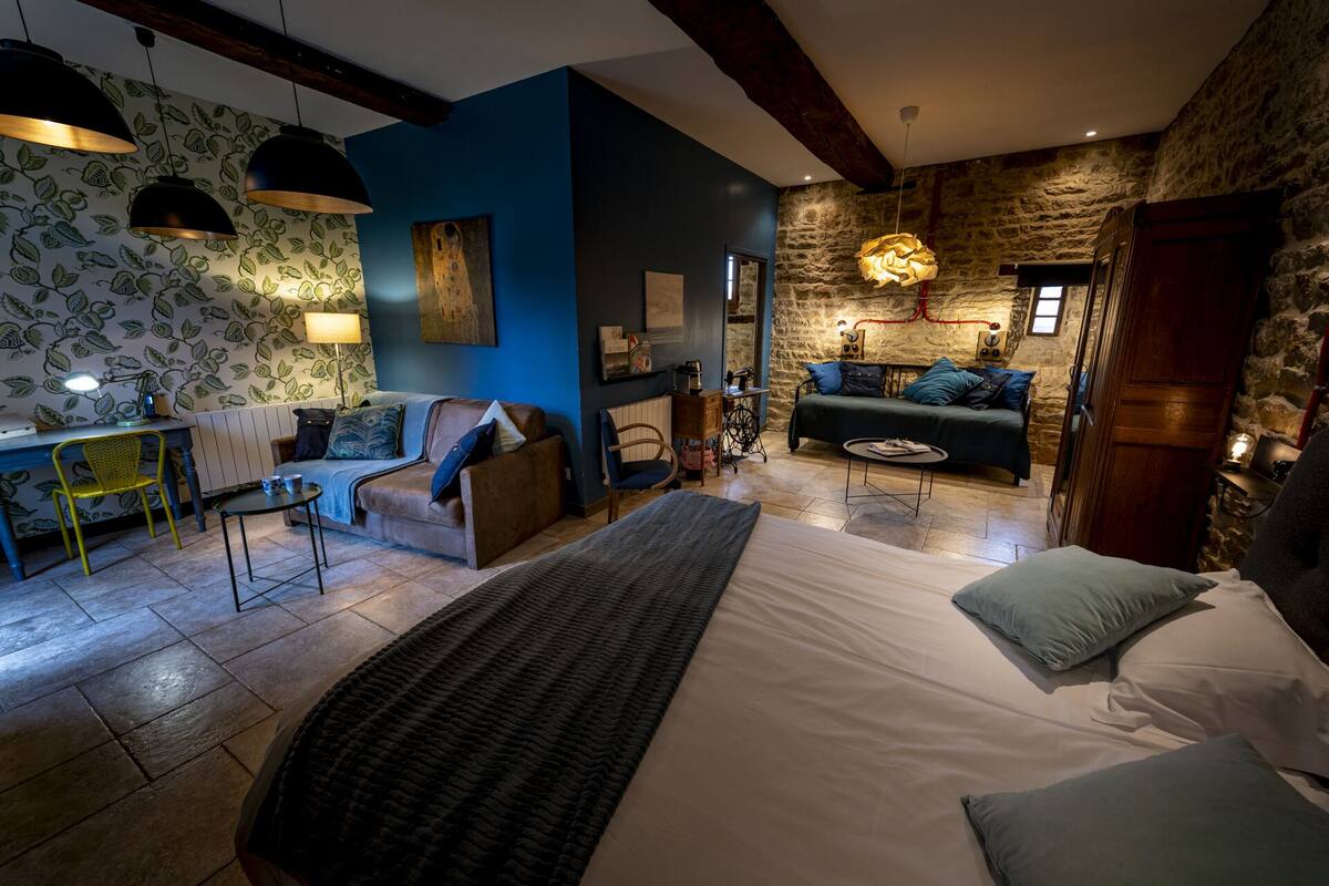 A cozy bedroom with a large bed, a desk, and a sofa.