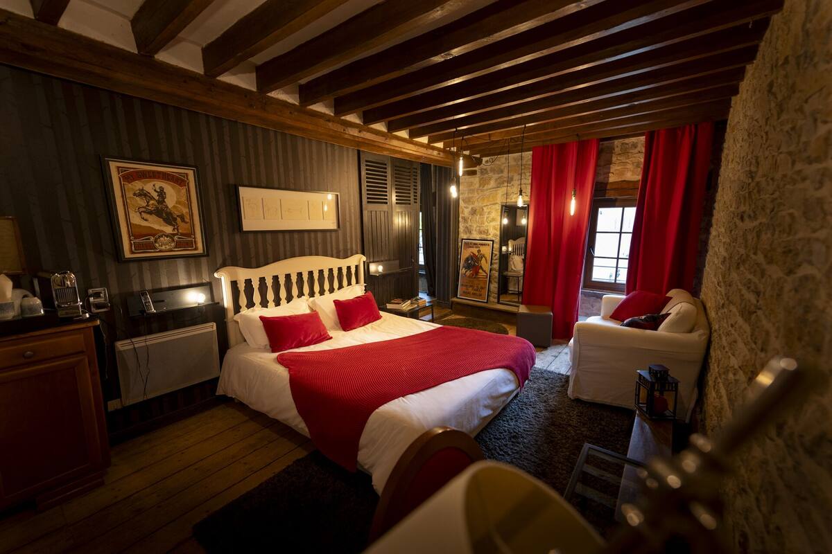 A bedroom with a bed, a desk, a chair, and a red curtain.