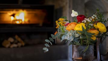 Un jarrón con una variedad de flores frente a una chimenea.