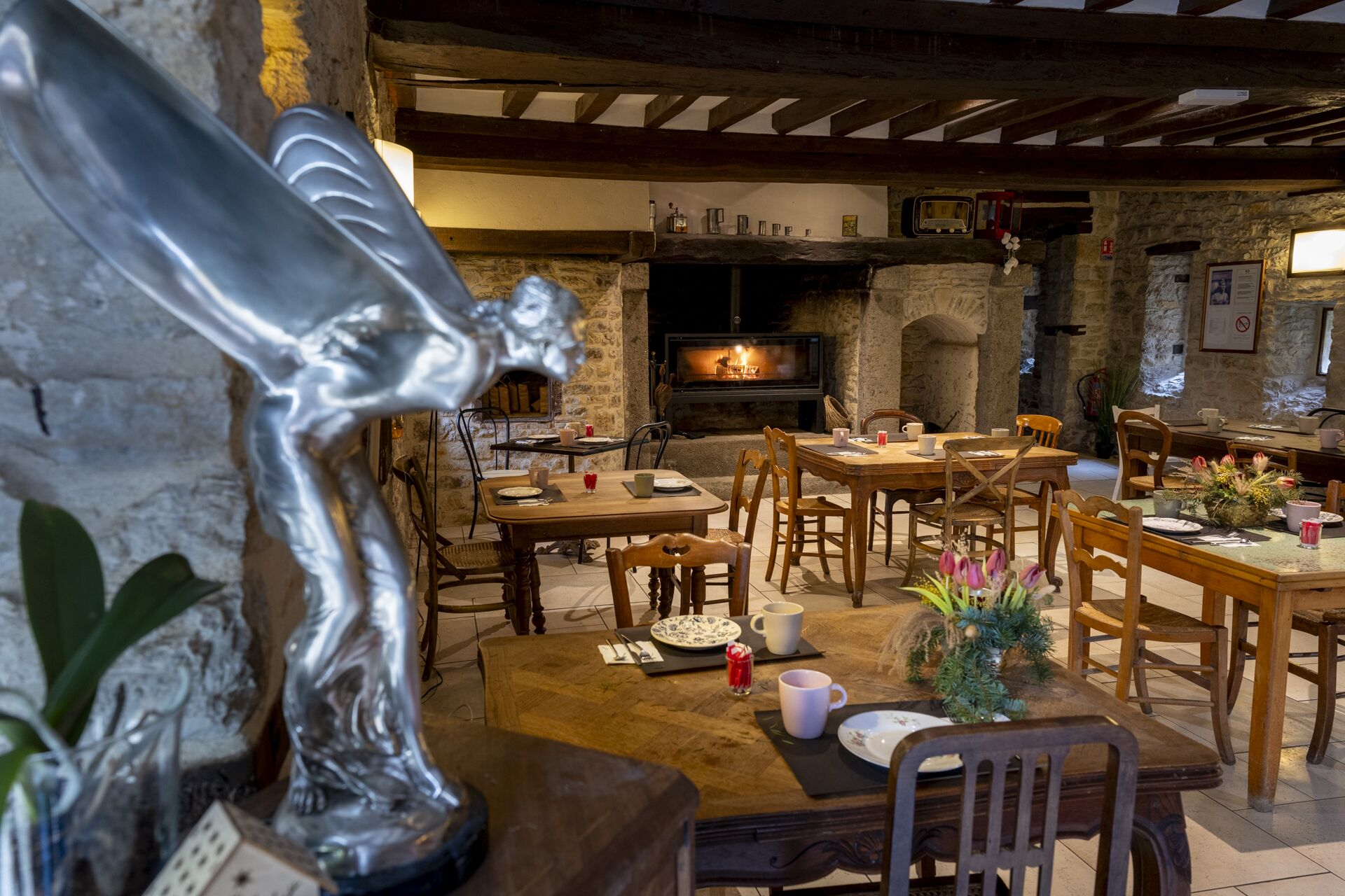 A rustic dining area with stone walls, wooden furniture, and a fireplace.
