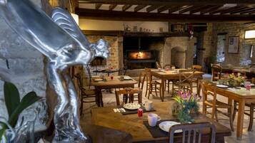 A rustic dining area with stone walls, wooden furniture, and a fireplace.