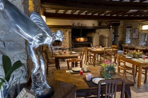 A rustic dining area with stone walls, wooden furniture, and a fireplace. - Au Domaine de la Pommeraye & Spa (La Pommeraye)