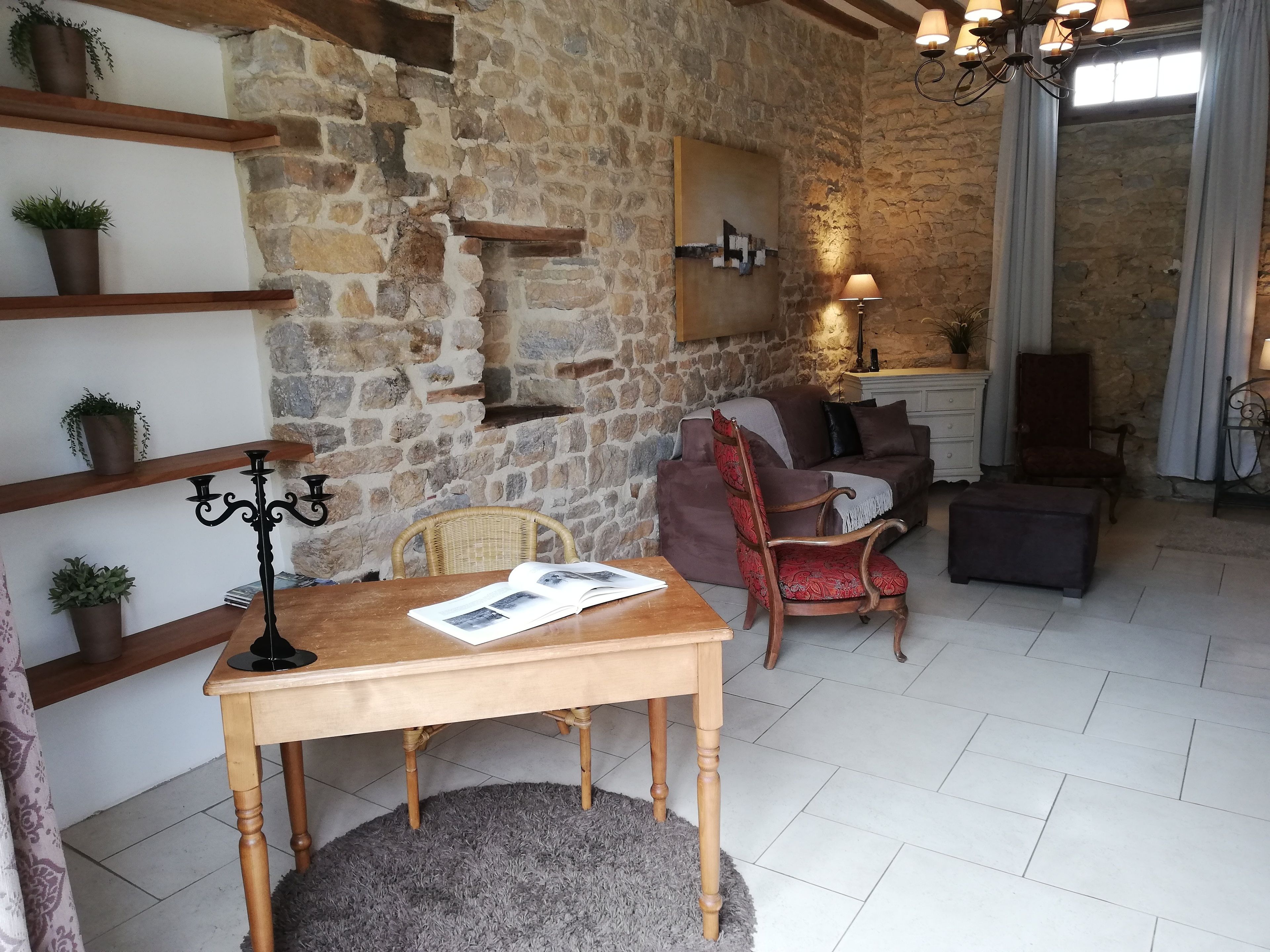 Un salón acogedor con pared de piedra, muebles de madera y un candelabro.