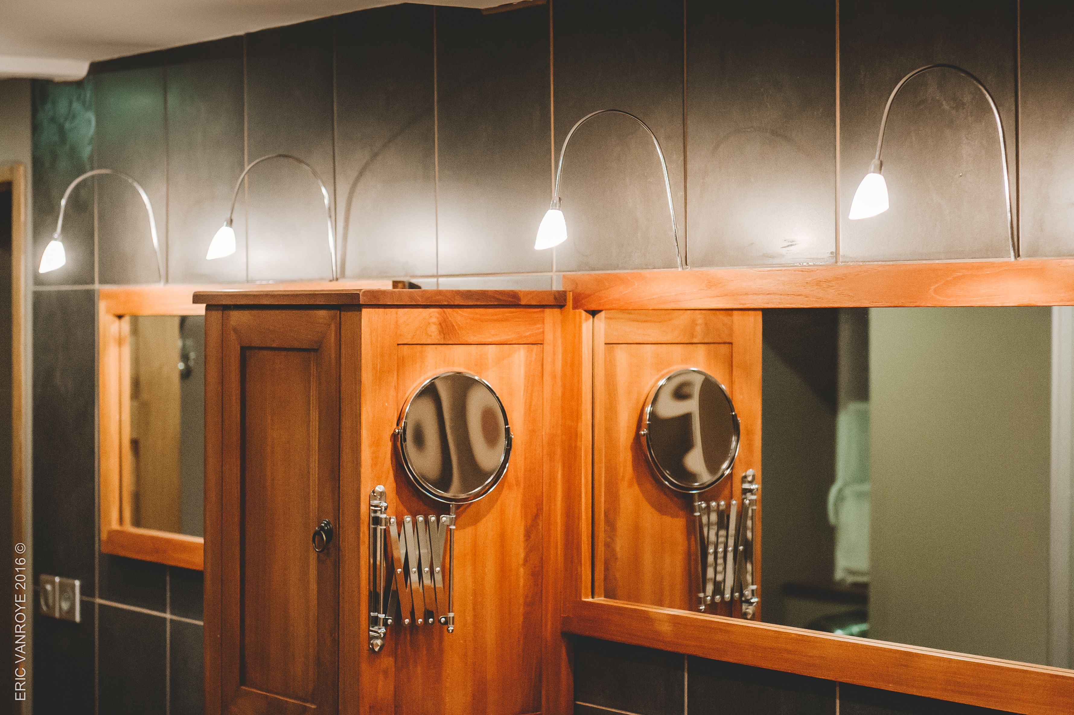 Un baño con tocadores de madera, espejos redondos e iluminación empotrada.