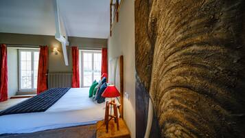 Un dormitorio con una cama, un taburete de madera, una lámpara roja y una pared grande con textura.