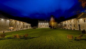 A stone building with a central lawn and chairs, illuminated by warm lights. - Au Domaine de la Pommeraye & Spa (La Pommeraye)