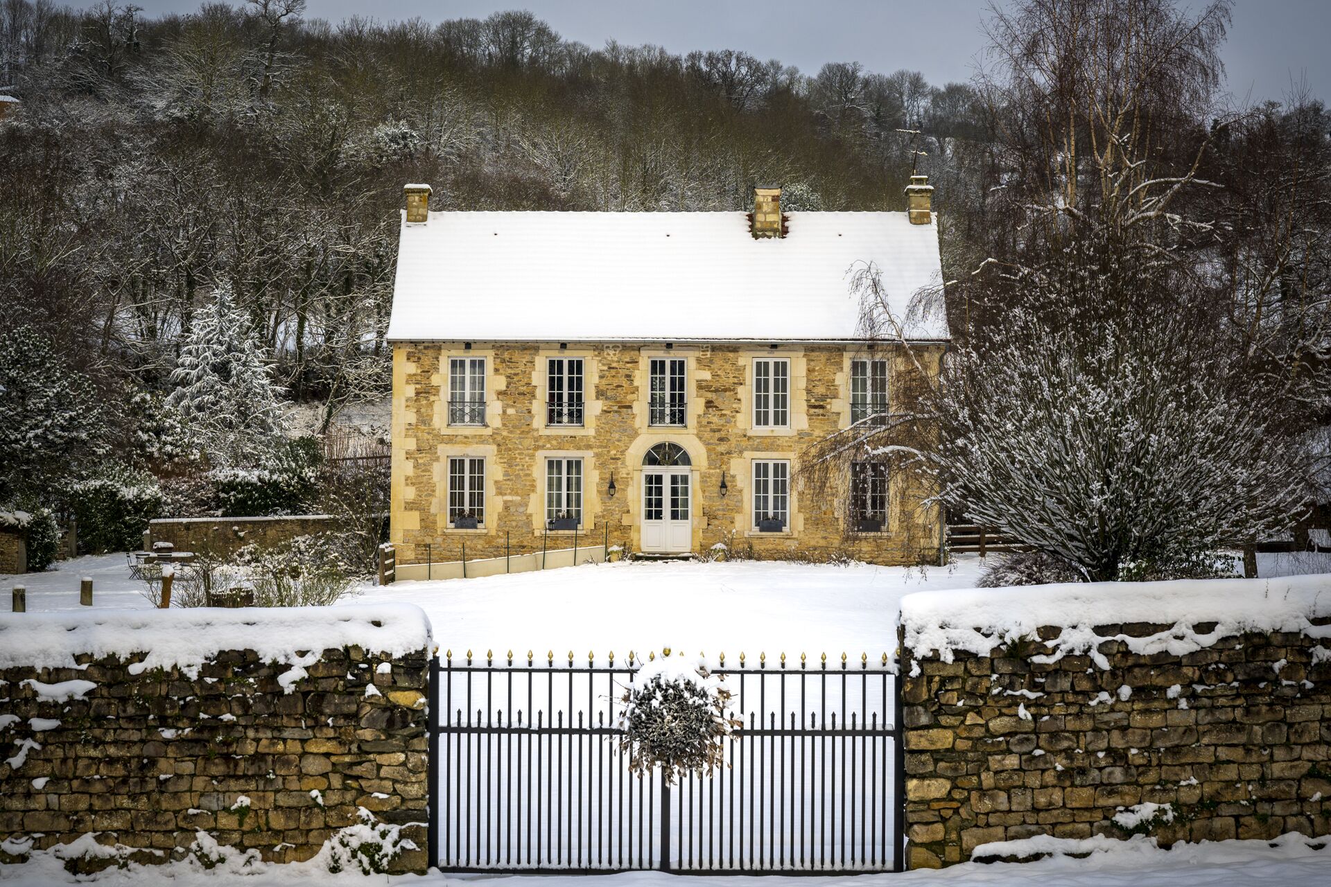 A stone building with a snow-covered roof and a gated entrance.