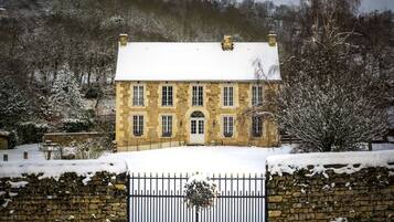 A stone building with a snow-covered roof and a gated entrance.