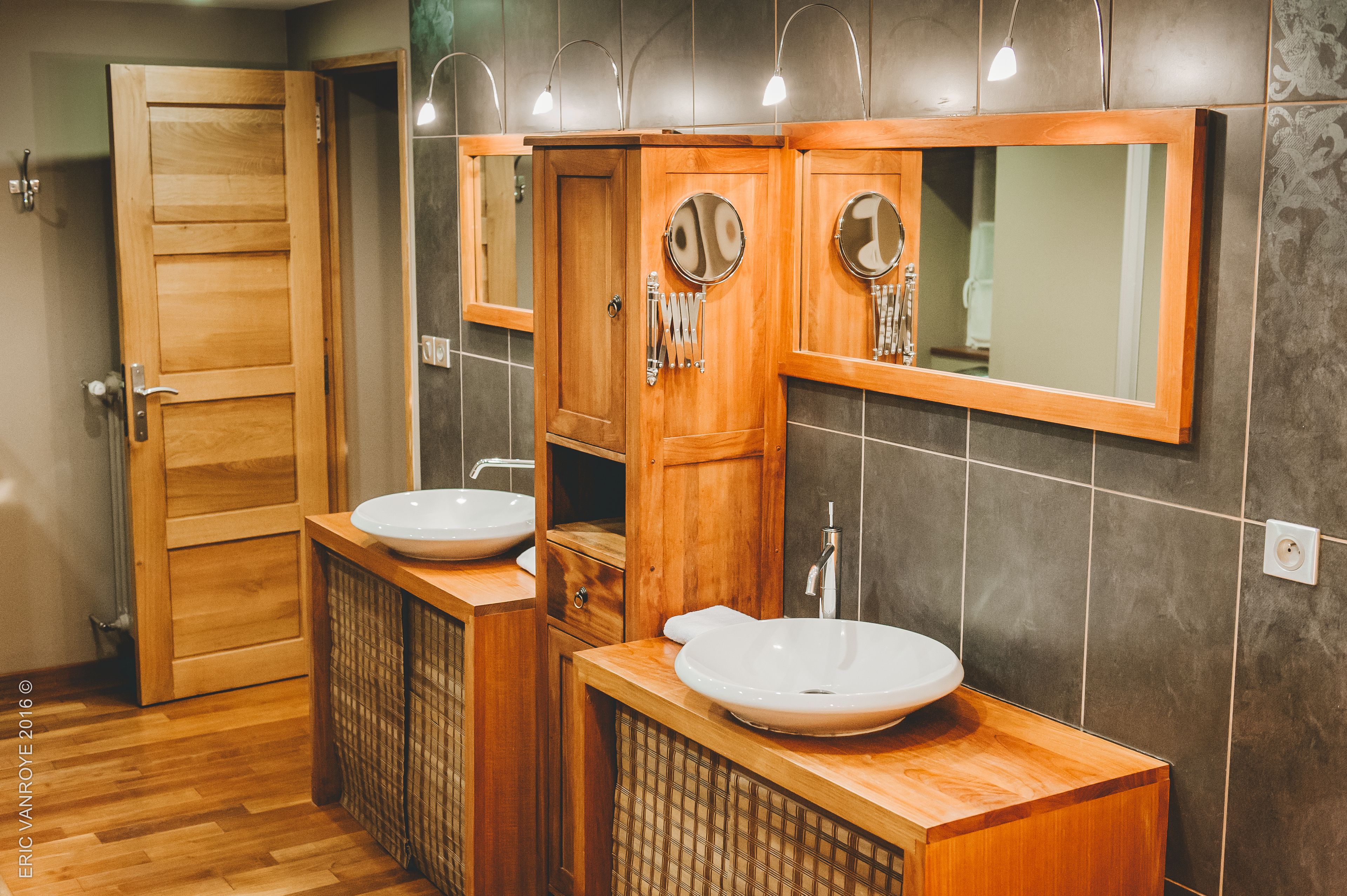 A bathroom with two sinks, wooden cabinets, and a mirror.
