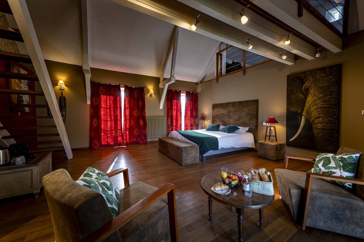 A spacious room with a large bed, a dining table with breakfast, and a view of the outdoors.