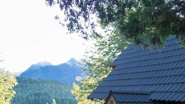 A wooden cabin with a deck overlooking a lake and mountains. - Cocos Cura Casas de Montaña (San Carlos de Bariloche)