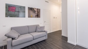 A modern living room with a grey sofa, dark tiled flooring, and two wall-mounted artworks. - Residenza Ottaviano 105 by Hili (Rome)