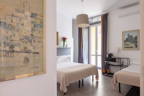 A hotel room with two beds, a large painting, a desk with a lamp, and a view of the outside. - Residenza Ottaviano 105 by Hili (Rome)
