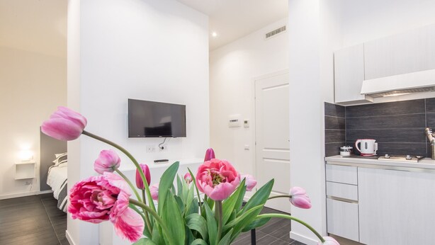A modern kitchen with white cabinets, a flat-screen TV, and a coffee maker on the counter. - Residenza Ottaviano 105 by Hili (Rome)