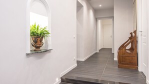 A modern hallway with a potted plant, a wooden sculpture, and a staircase. - Residenza Ottaviano 105 by Hili (Rome)