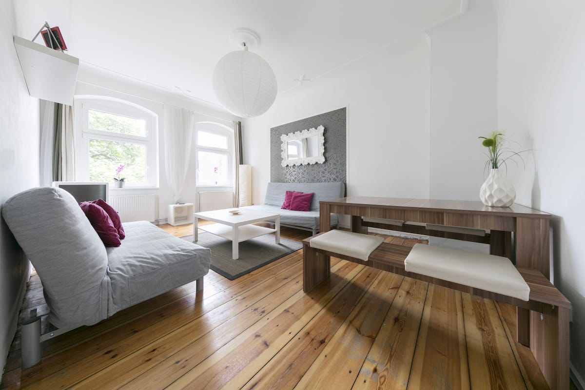 A modern living room with a grey sofa, white coffee table, wooden bench, and a grey patterned wall.