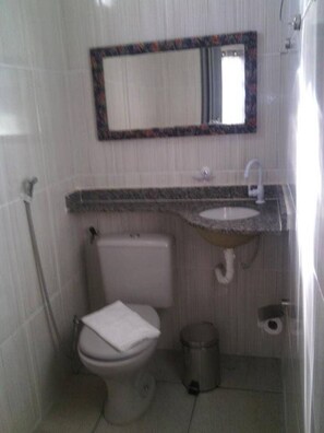 A small bathroom with a toilet, sink, and mirror. - Pousada Palace Nook (Olímpia)
