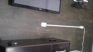 Un mueble bajo de madera oscura con cajones, un televisor de pantalla plana montado en la pared y un pequeño electrodoméstico blanco en el suelo.
