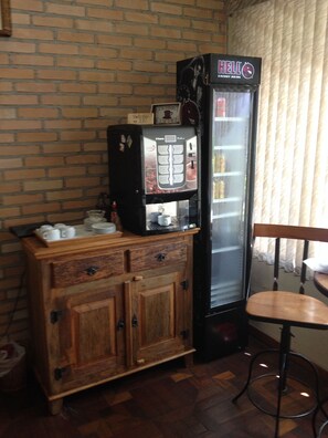 A coffee machine and a refrigerator in a room with a brick wall and wooden furniture. - Pousada Ibituruna (São Paulo)