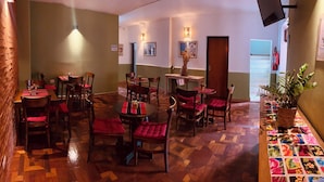 Un restaurante con piso de madera, sillas tapizadas de rojo y mesas con individuales.