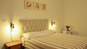 Un dormitorio con edredón a rayas, cabecero tapizado, lámparas de noche y mesita de noche.