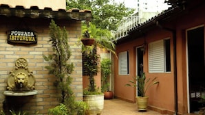 Un patio con una fuente, plantas en macetas y un letrero que dice "Pousada Ibituruna".