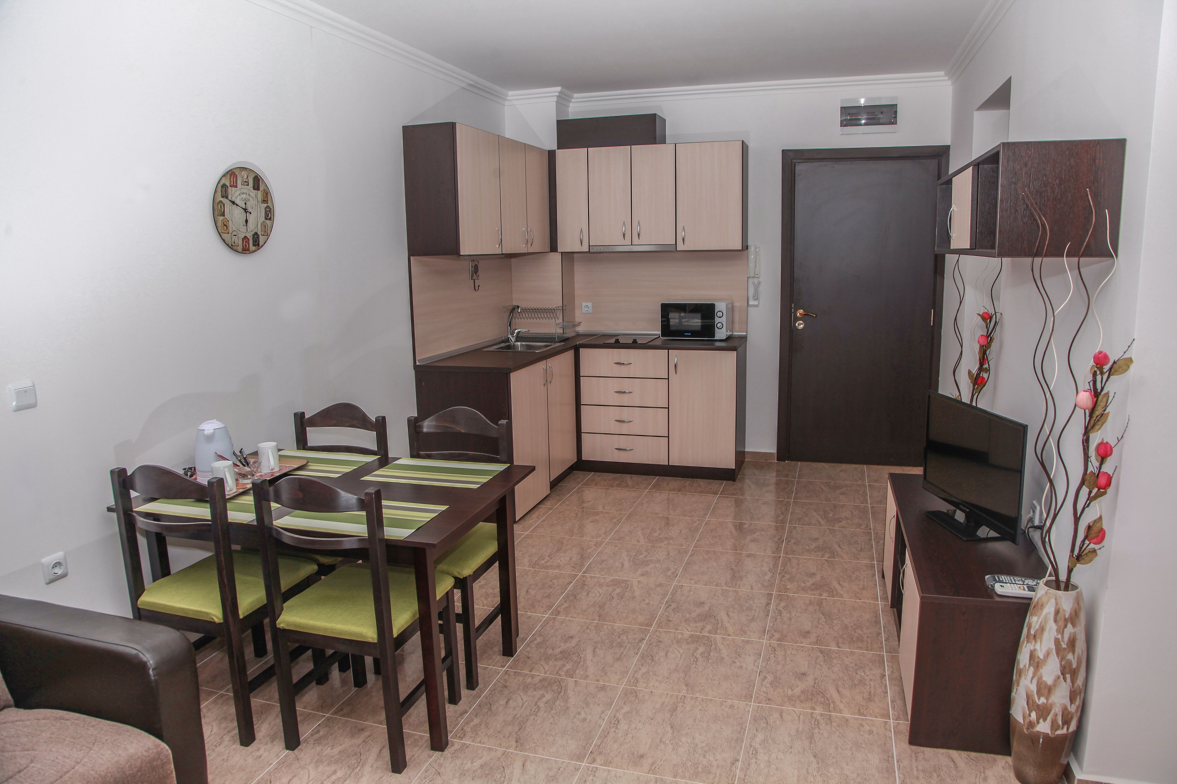 A compact kitchen with a microwave, sink, and cabinets. There is a dining area with a table and chairs.