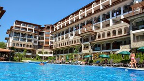 Un hotel con piscina, varios balcones y zonas de estar al aire libre.