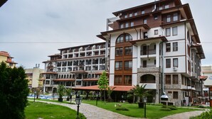 Un hotel de varios pisos con un patio, mobiliario exterior y un camino de piedra.