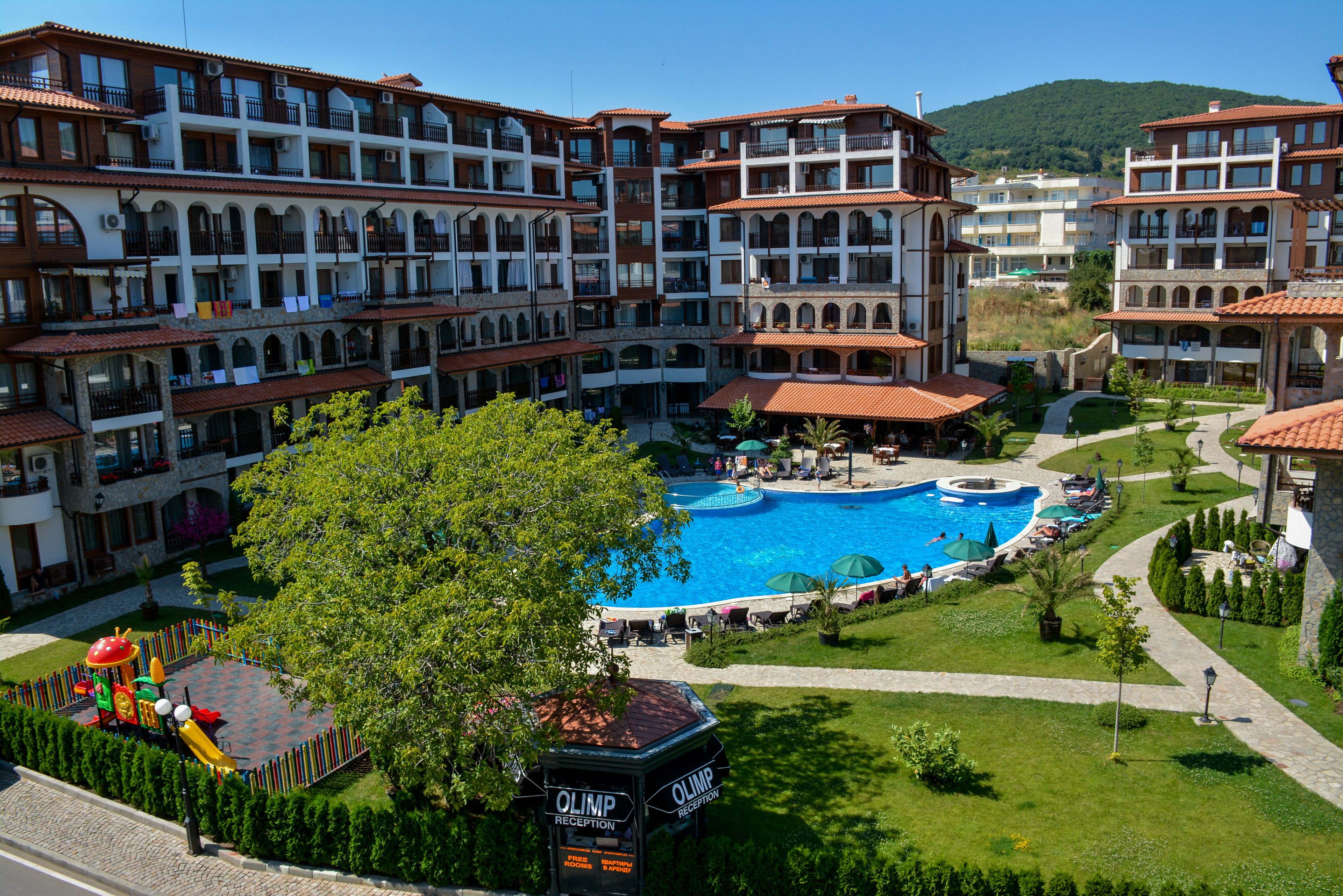 A hotel with multiple balconies, a central swimming pool, and a children's play area.