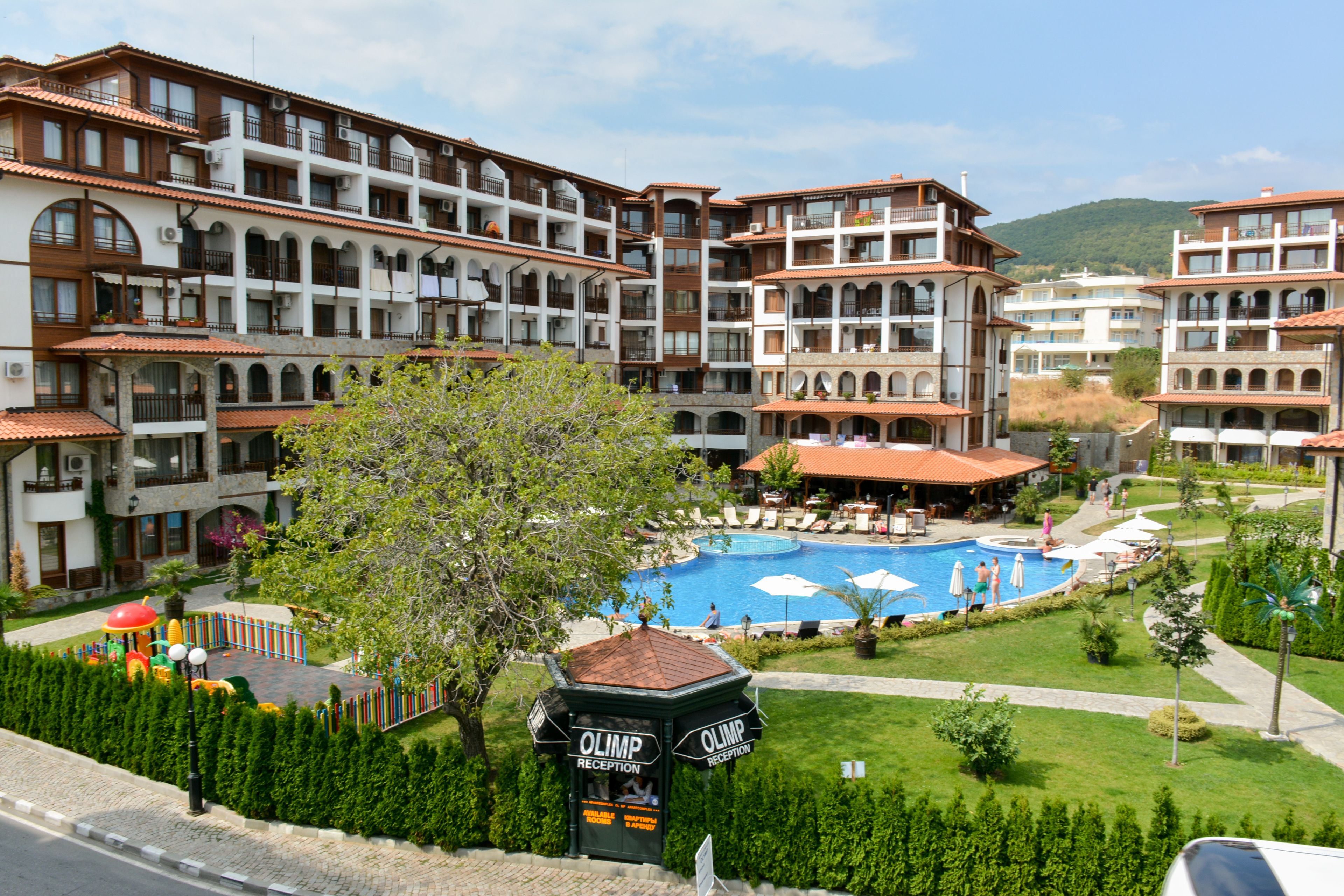 A hotel with multiple balconies, a swimming pool, and a reception area.