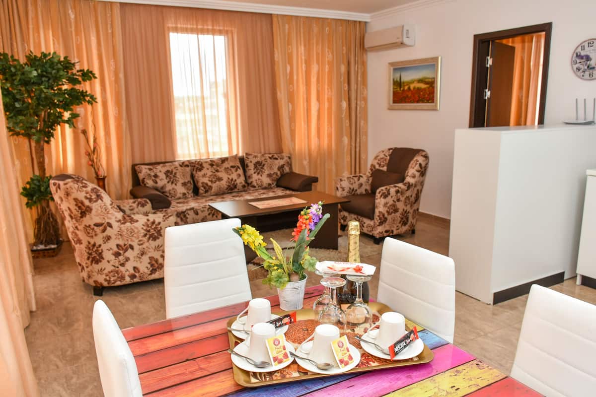 A cozy living room with a sofa set, a dining table with a tray of food, and a potted plant.