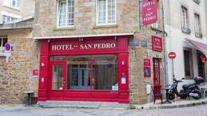 Ein Gebäude aus Stein mit einer roten Fassade, auf der „HOTEL SAN PEDRO“ steht.