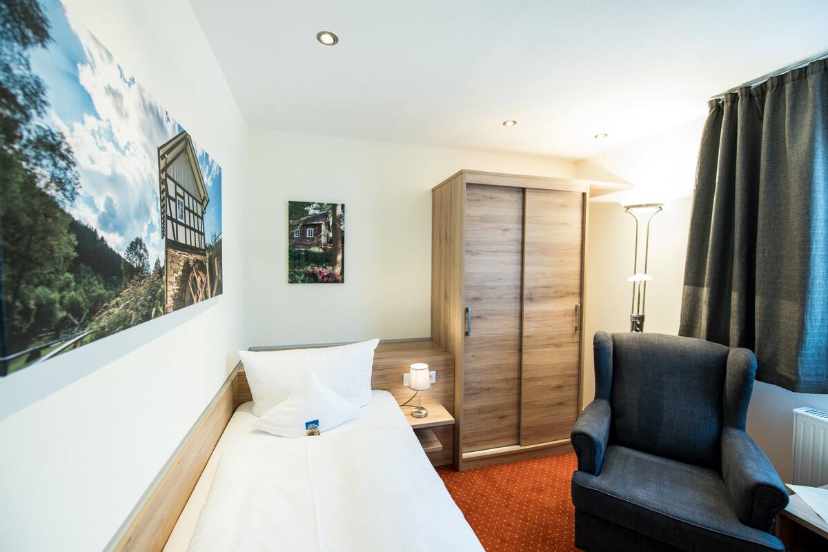 Une chambre d’hôtel comprenant un lit, une armoire, une chaise, une table de chevet et une lampe.