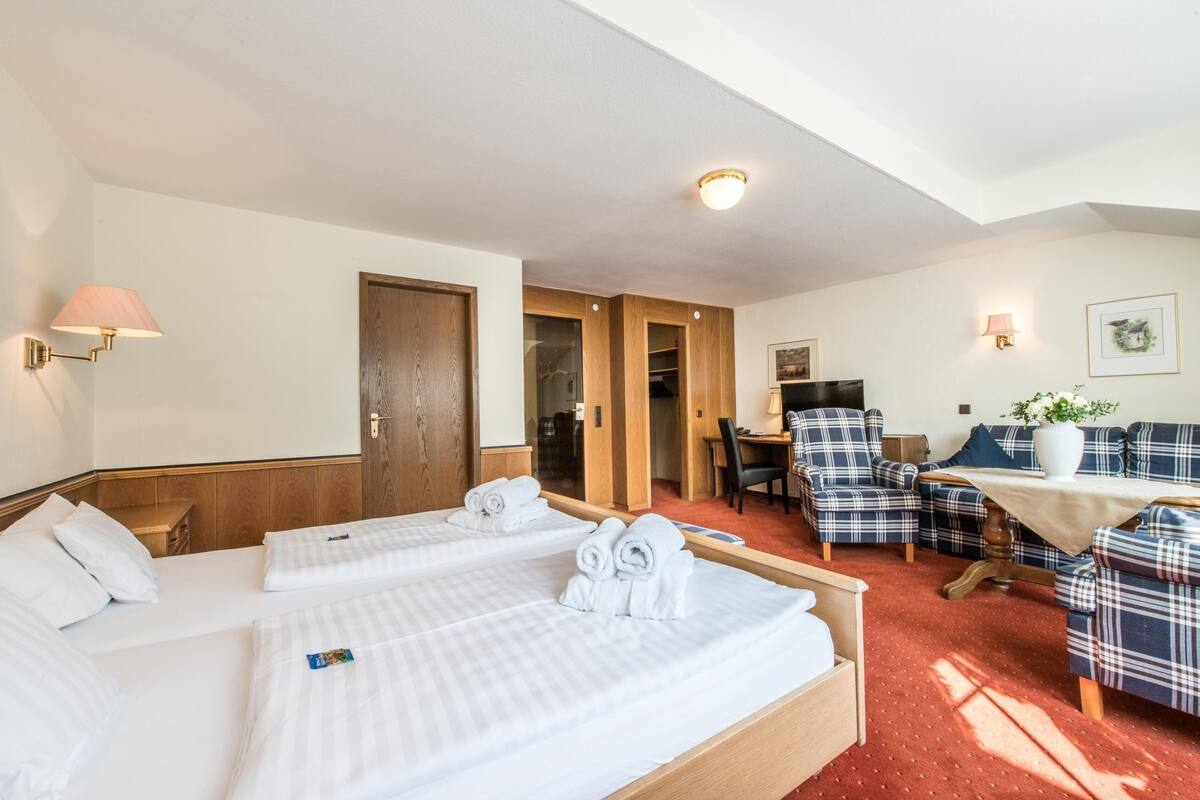 Une chambre d’hôtel avec deux lits, un bureau, une chaise et un canapé.