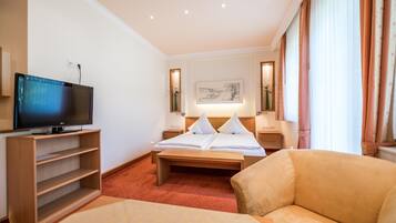 Una habitación de hotel con una cama, televisión, escritorio y una silla.