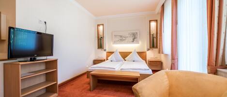 Una habitación de hotel con una cama, televisión, escritorio y una silla.
