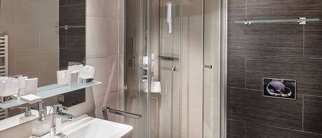 A modern bathroom with a glass-enclosed shower, a white sink, and a toilet.