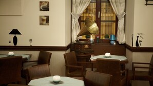 A cozy dining area with wooden tables and chairs, a gramophone, and wall decorations including framed pictures and a cat silhouette. - Boutique Hotel Chrysso (Kosice)