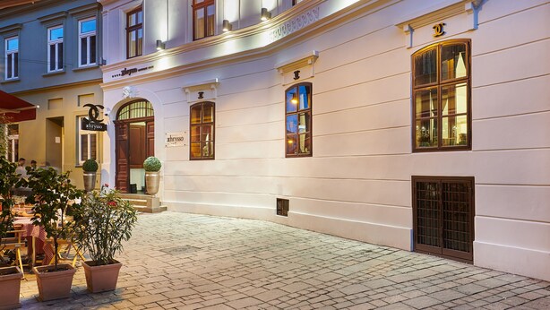 A historic building with a grand entrance, multiple windows, and a cobblestone courtyard. - Boutique Hotel Chrysso (Kosice)
