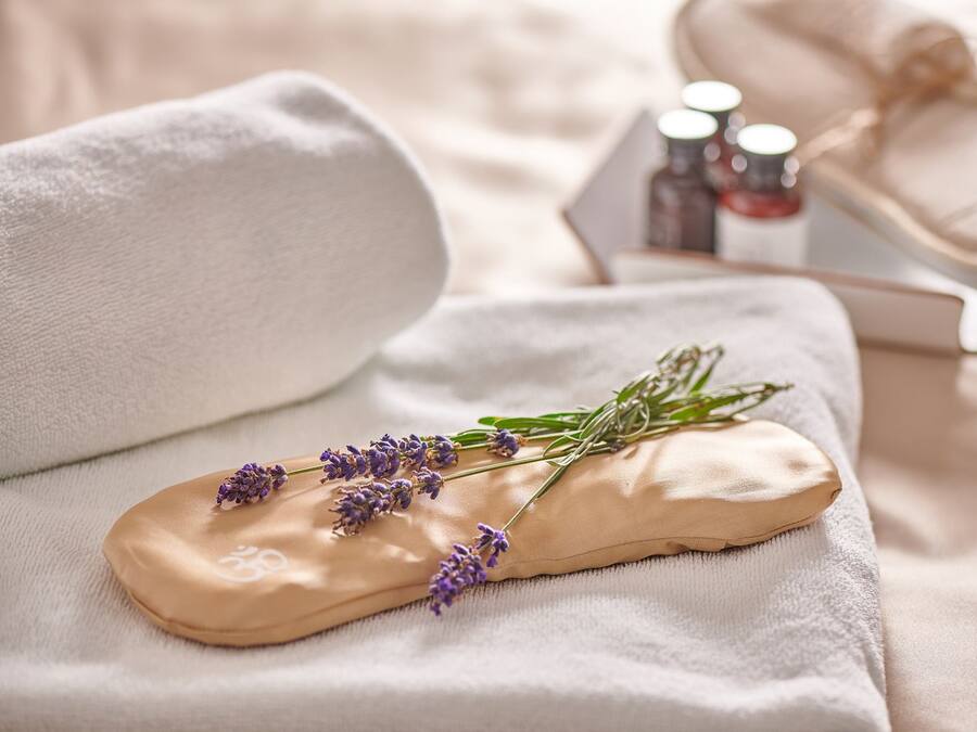 A massage tool with lavender on a towel, a small bag, and two bottles of oil.