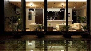 A modern interior with a reflective floor, potted plants, and a chandelier. - Boutique Hotel Chrysso (Kosice)