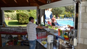 Un espace bar offrant une vue sur une piscine et les clients.