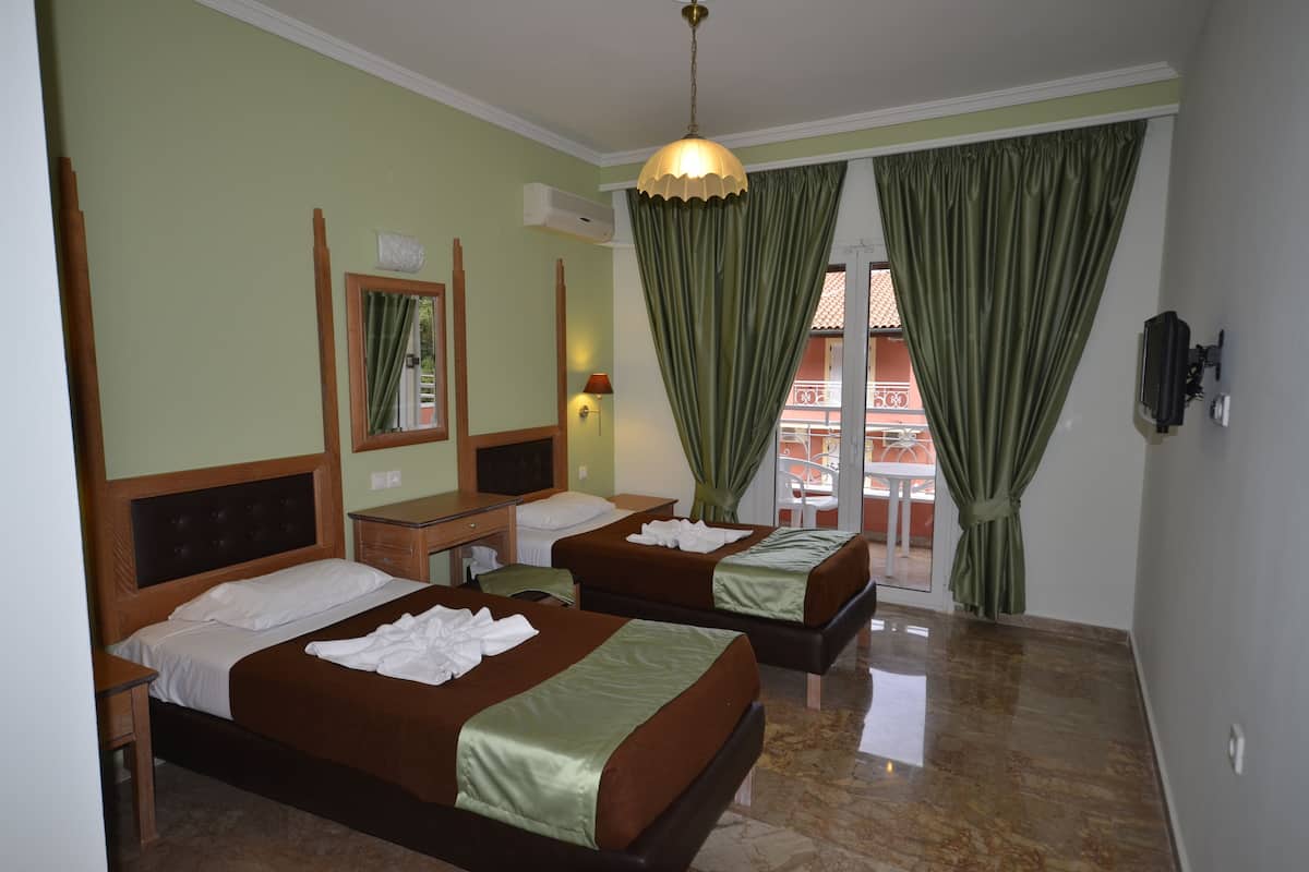 A hotel room with two beds, a mirror, a TV, and a balcony with a view.