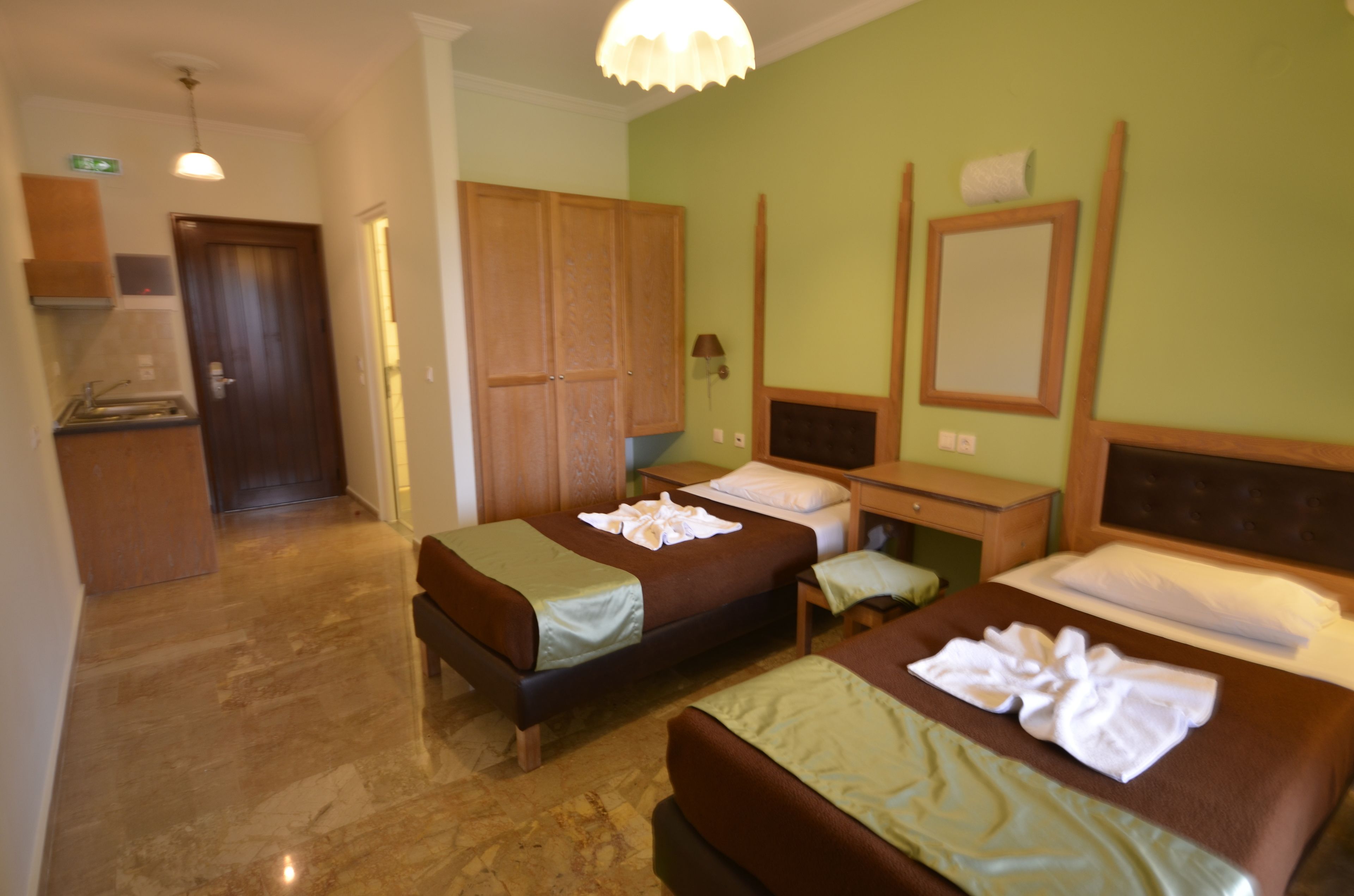 A hotel room with two beds, a desk, a mirror, and a wardrobe.
