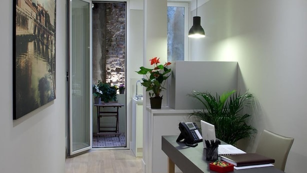 A modern office space with a desk, chair, and potted plants. - Regola Suite (Rome)