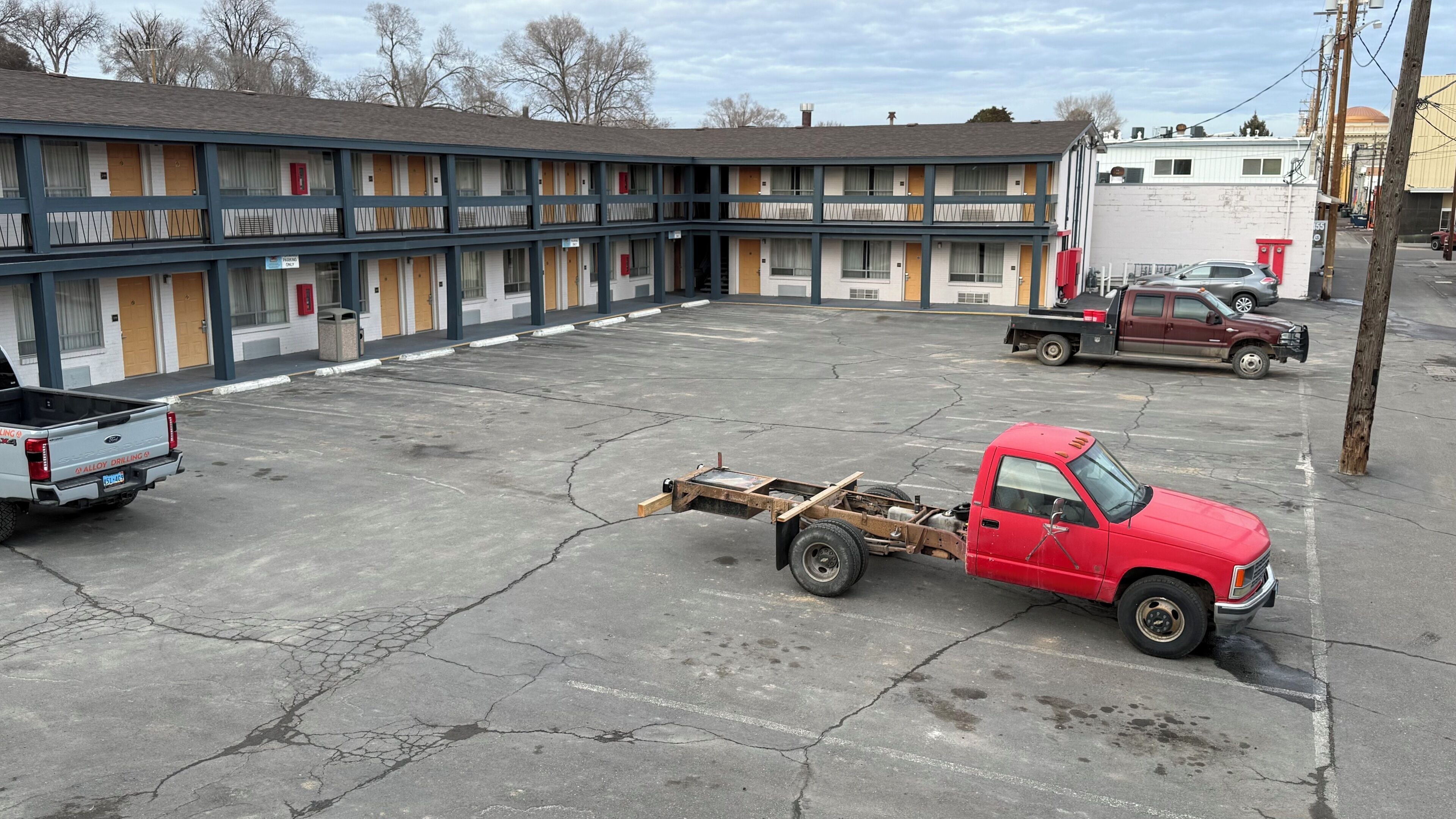 A motel with multiple rooms, a parking lot, and a red truck.