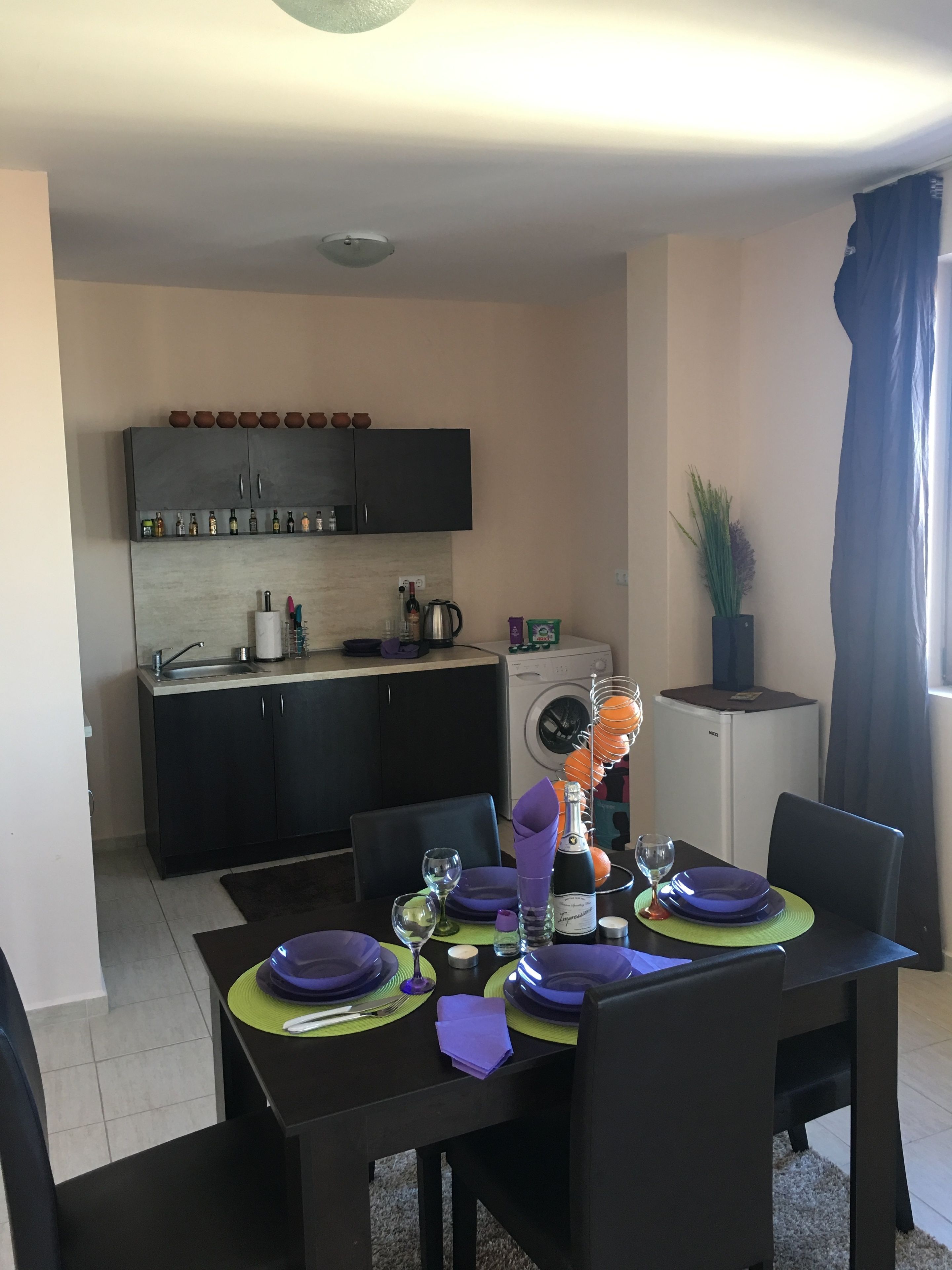 Una cocina compacta con armarios oscuros, una lavadora y un refrigerador pequeño.